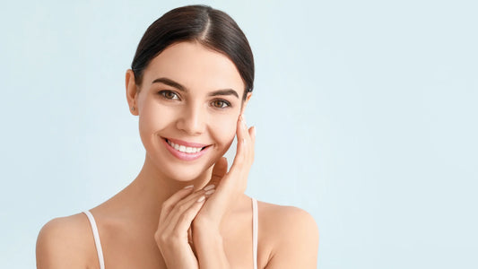 A young woman with glowing skin smiling and touching her face, representing the secret power of vitamin K2 for skin health.