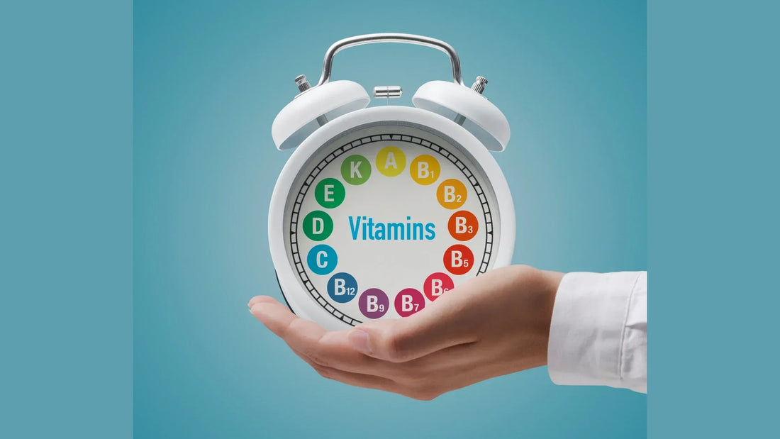 A white alarm clock displaying various vitamins, held in a person’s hand against a blue background, symbolizing the importance of taking Vitamin D3 and K2 for overall health.